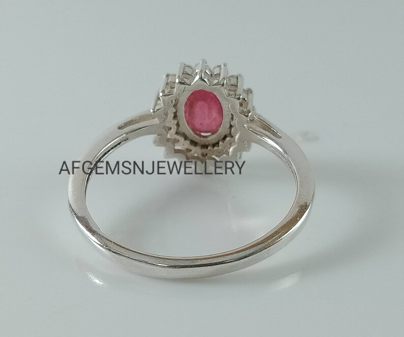 Pu&ograve; includere: Un anello d'argento con una pietra ovale rosa circondata da pietre bianche pi&ugrave; piccole. L'anello &egrave; incastonato in un design floreale.