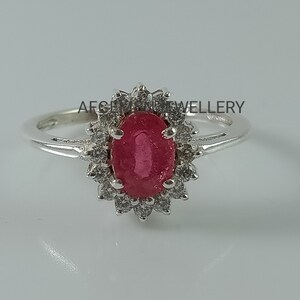 Pu&ograve; includere: Un anello d'argento con un grande rubino ovale circondato da pietre bianche pi&ugrave; piccole.