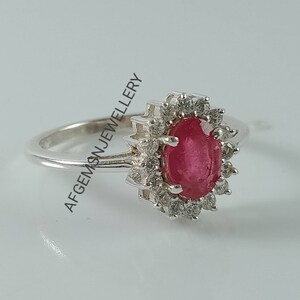 Pu&ograve; includere: Un anello d'argento con un grande rubino ovale circondato da pietre bianche pi&ugrave; piccole.