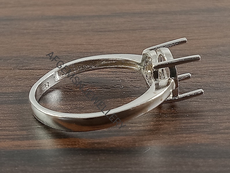 May include: Silver ring setting with a round bezel for a gemstone. The ring is plain and has a smooth band.