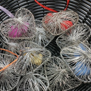 Peut inclure: Un panier rempli d'ornements en forme de cœur en fil d'argent. Chaque cœur contient une pierre de couleur différente, dont du rose, du rouge, du jaune, du bleu et du bleu clair.