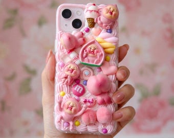 Op de afbeelding: Roze telefoonhoesje met een grillig ontwerp met roze cartoonfiguren, perziken, ijs en snoep. De hoes heeft een getextureerde, matte uitstraling met een verscheidenheid aan 3D-versieringen. Het ontwerp bevat het woord "milk".