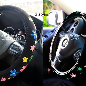 May include: Two black steering wheel covers with floral embroidery. One cover has the text "Steering Wheel Cover w/ Grip Inside". The other cover has the text "Elastic Steering Wheel Cover". The flowers are in various colours.