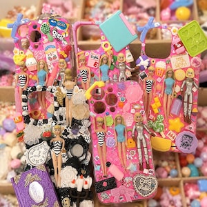 Peut inclure: Trois coques de téléphone décorées de poupées miniatures en plastique, incluant des figurines en maillot de bain et en combinaison spatiale, ainsi que divers charms colorés comme des aliments, miroirs, horloges et nœuds. Les coques présentent un collage dense d'accessoires en plastique aux tons rose vif, bleu et blanc.