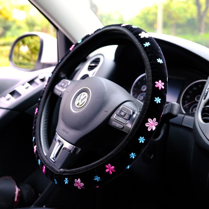 May include: Black steering wheel cover with pink and blue embroidered flowers.