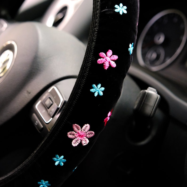 May include: Black steering wheel cover with pink and blue embroidered flowers.