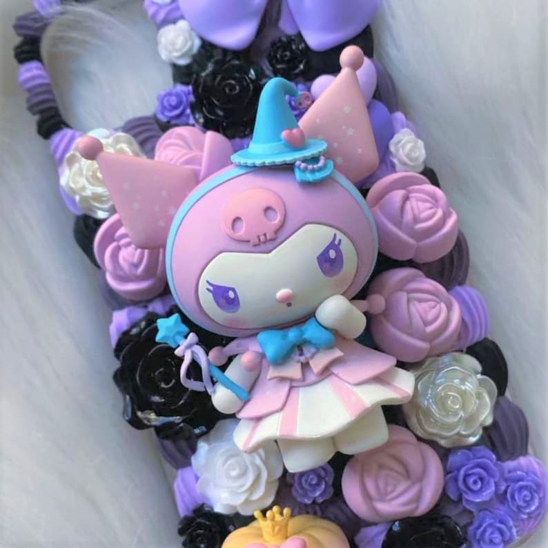 Puede incluir: Un personaje rosa y morado con una calavera en la frente que lleva un sombrero de bruja azul y un vestido rosa y blanco. El personaje sostiene una varita azul y blanca con una estrella en el extremo. El personaje est&aacute; rodeado de flores rosas, moradas y blancas.