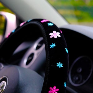 May include: Black steering wheel cover with pink and blue embroidered flowers.