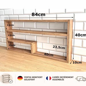 Könnte beinhalten: Ein rechteckiges Wandregal aus Holz mit drei Ebenen, 84 cm breit, 40 cm hoch und 10 cm tief. Das Regal hat eine hellbraune Holzmaserung, mit Fachhöhen von 11 cm, einer 23,5 cm breiten Öffnung und einem 40 cm breiten unteren Bereich.