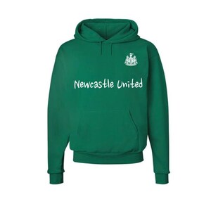 May include: A green hooded sweatshirt with the text "Newcastle United" in white across the chest. The sweatshirt features a kangaroo pocket and a white emblem on the upper chest. The hoodie has a drawstring and a hood.