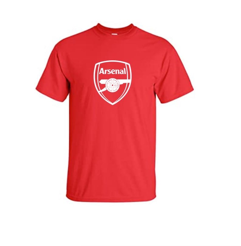 May include: Red t-shirt with the Arsenal logo printed on the front. The logo is a white shield with the word "Arsenal" above a cannon. The shirt is made of a comfortable fabric.