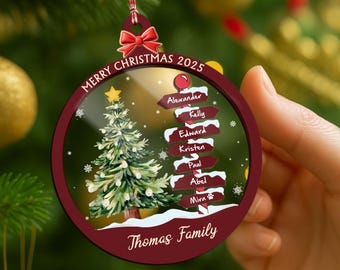 May include: A round Christmas ornament with a red border and a festive design. The ornament features a Christmas tree, snowflakes, and the text "Merry Christmas 2025" and "Thomas Family". It also includes names on directional signs.