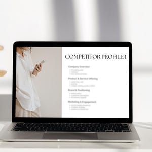 May include: A laptop computer screen displaying a competitor profile template with the heading "Competitor Profile I". The template includes sections for company overview, product and service offerings, brand and positioning, and marketing and engagement.