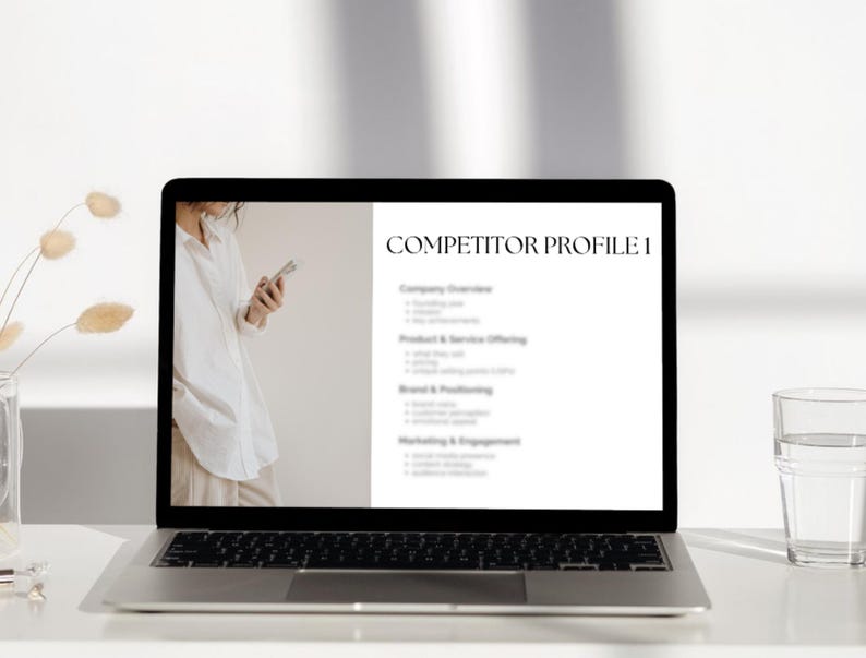 May include: A laptop computer screen displaying a competitor profile template with the heading "Competitor Profile I". The template includes sections for company overview, product and service offerings, brand and positioning, and marketing and engagement.