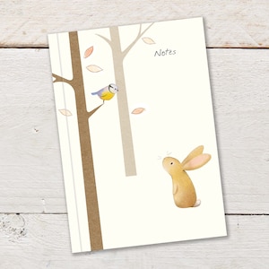 A6 96pps Notizbuch mit niedlichem Kaninchen und Blaumeise die im Baum sitzen, auf cremefarbenem Hintergrund mit &quot;Notes&quot; Beschriftung. Notebook ist liniert.