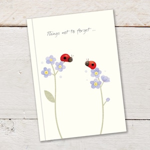 Op de afbeelding: Een witte kaart met de tekst "Things not to forget..." in zwarte cursieve letters. Twee rode lieveheersbeestjes zitten op blauwe vergeet-me-nietjes.