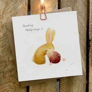 Carte d’anniversaire, carte Get Well, carte Hugs mettant en vedette un lapin étreignant un hérisson. La carte a une feuille en creux.