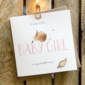 Tarjeta para niña, hermosa niña, nuevo bebé, nacimiento felicidades. Cuenta con un pequeño conejo bebé y una mariquita. Con un accesorio de hoja de madera