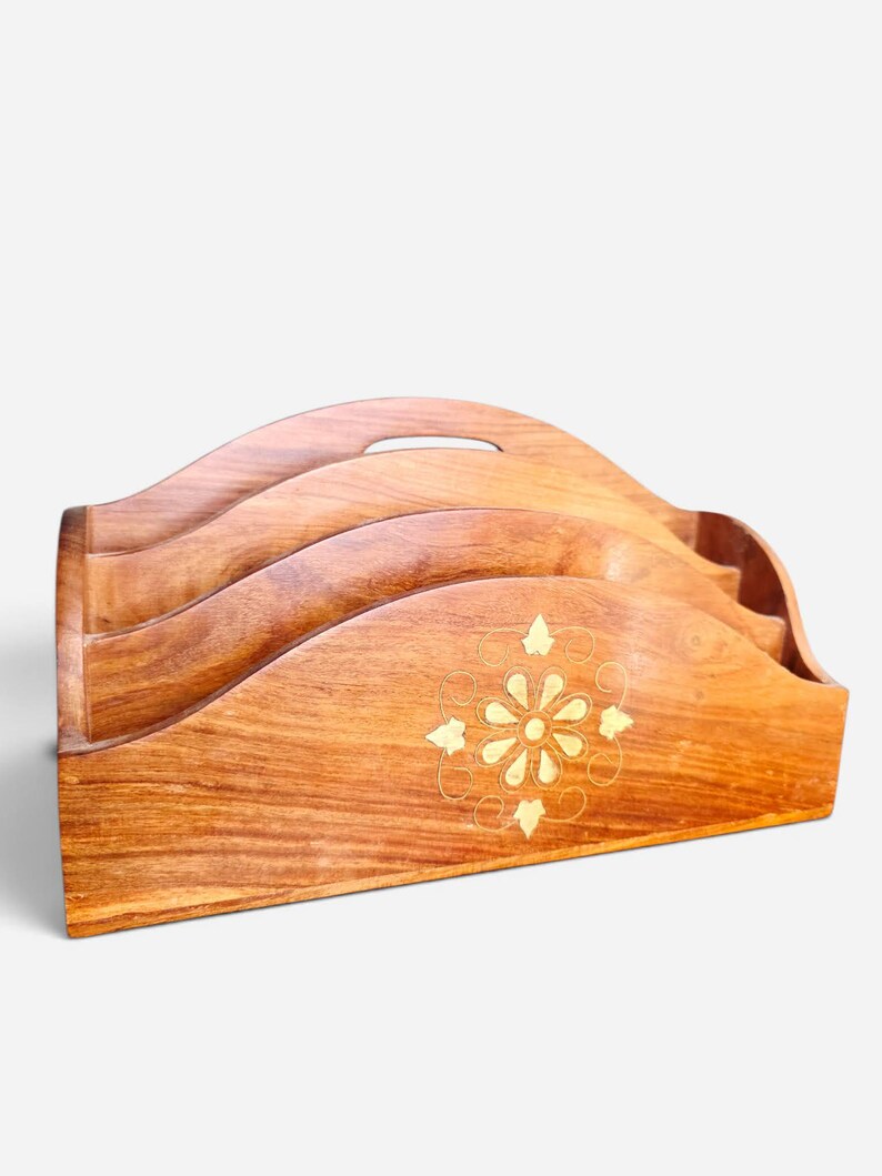 May include: A wooden letter holder featuring three tiered compartments with wavy edges. The front panel is decorated with a central brass inlay depicting a stylized flower surrounded by delicate swirling lines and small leaf-shaped accents.