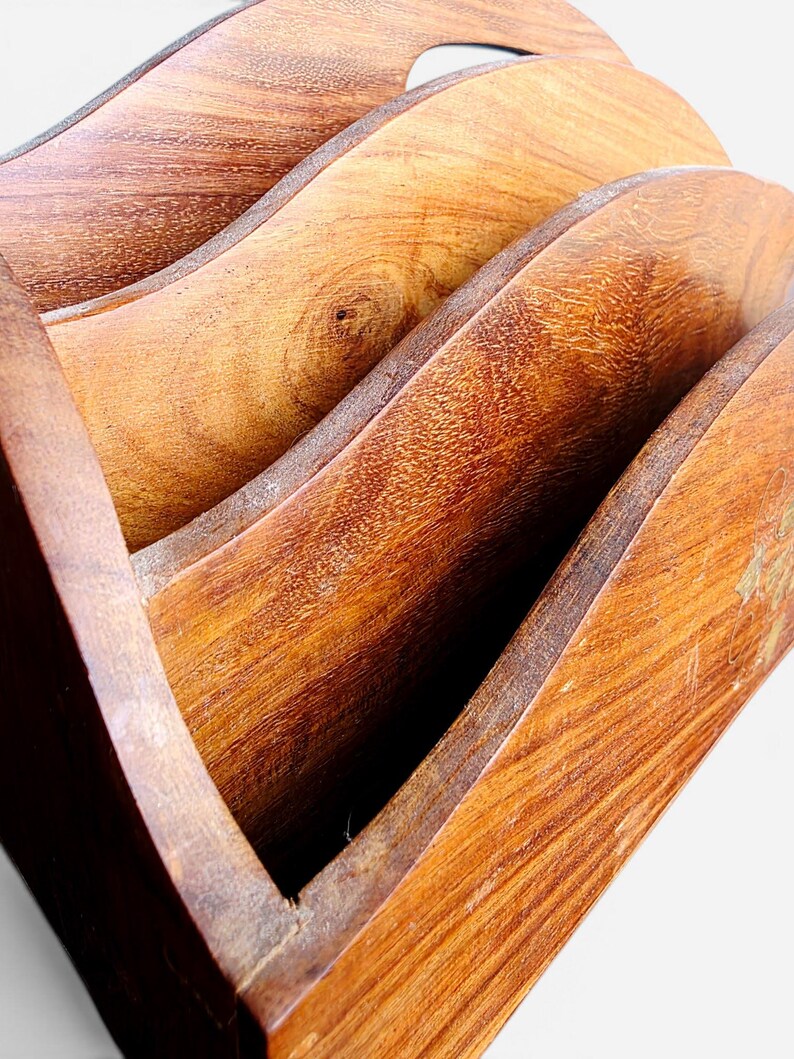 May include: A wooden letter holder featuring three curved, tiered compartments with a visible natural wood grain pattern. The structure is crafted from polished brown wood, showcasing distinct knots and textures across the arched dividers.