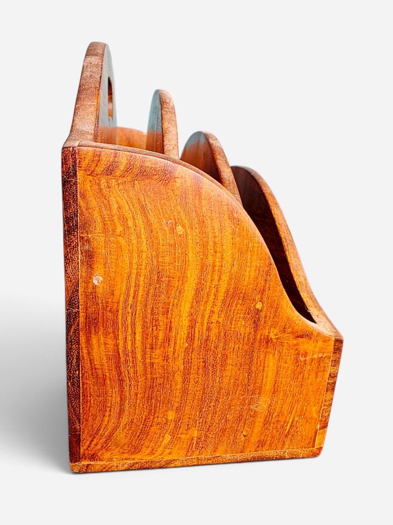 May include: A wooden desk organizer with a natural grain finish, featuring three tiered compartments with curved side panels. The structure is made of light brown wood with visible vertical grain patterns and rounded edges on each divider section.