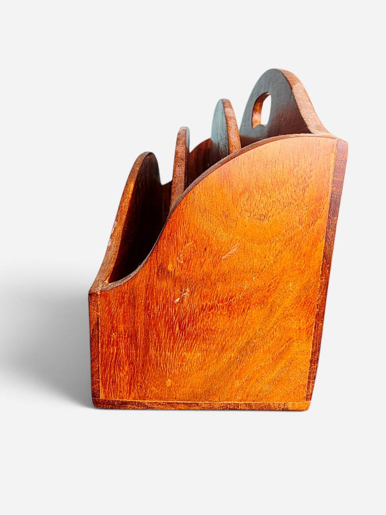 May include: A wooden desk organizer with a warm brown finish and visible wood grain. The organizer features three tiered compartments with curved side panels and a cutout handle at the top, providing a structured space for holding documents or mail.