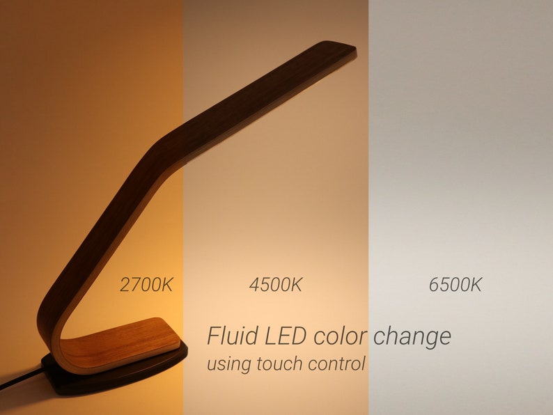 May include: A wooden desk lamp with a curved arm and a touch-sensitive base. The lamp has three different color temperature settings: 2700K, 4500K, and 6500K. The text "Fluid LED color change using touch control" is displayed below the lamp.
