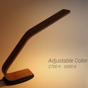 May include: A wooden desk lamp with an adjustable arm and a black base. The lamp has an adjustable color temperature, ranging from 2700K to 6500K.