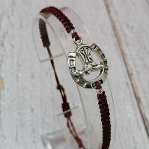 May include: A brown braided cord bracelet with a silver horseshoe charm featuring a boot design.