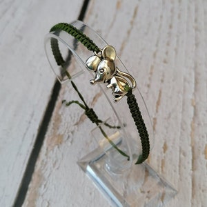 May include: A green friendship bracelet with a silver mouse charm.