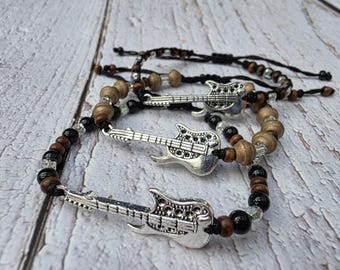 May include: Several beaded bracelets with silver guitar charms. The bracelets feature a mix of wooden, black, and clear beads. The guitar charms are detailed and add a musical theme to the jewelry.