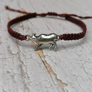 Op de afbeelding: Een bruin gevlochten koordarmband met een zilveren buffelbedel.