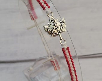 May include: Red and white braided bracelet with a silver maple leaf charm.
