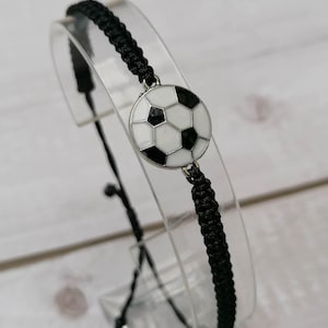 May include: Black braided bracelet with a silver football charm.