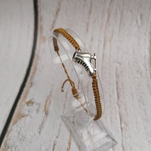 May include: A brown braided cord bracelet with a silver ice skate charm.