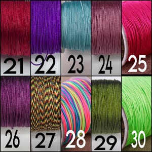 May include: A collection of ten spools of cord arranged in two rows, labeled 21 through 30. The cords feature various solid colors including red, purple, teal, pink, olive, and lime green, alongside two multicolored striped patterns.