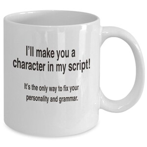 May include: White ceramic coffee mug with black text that reads "I'll make you a character in my script! It's the only way to fix your personality and grammar."