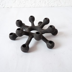 Può includere: Un portacandele in ghisa nera con un design a stella e dieci portacandele.