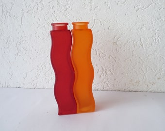 May include: Two wavy glass vases, one red and one orange.