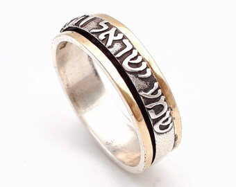 May include: A silver ring with a gold band and Hebrew writing around the band.