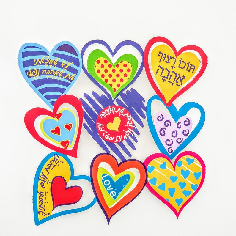 Puede incluir: Una colecci&oacute;n de ocho recortes de papel en forma de coraz&oacute;n de colores con texto en hebreo y dise&ntilde;os. Los corazones est&aacute;n dispuestos en c&iacute;rculo sobre un fondo blanco. El texto en los corazones incluye "Love", "Feliz cumplea&ntilde;os" y otras frases en hebreo.