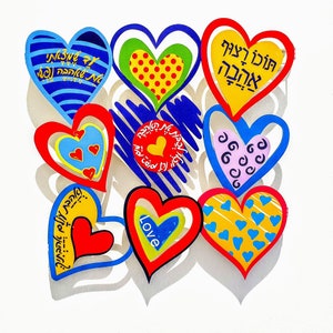 Puede incluir: Una colecci&oacute;n de nueve decoraciones de pared en forma de coraz&oacute;n de colores con texto en hebreo y la palabra "Love".