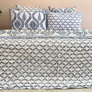 K&ouml;nnte beinhalten: Eine wei&szlig;e und blaue Steppdecke mit geometrischem Muster. Die Steppdecke ist aus Baumwolle und f&uuml;hlt sich weich und bequem an. Die Steppdecke ist perfekt, um jedem Schlafzimmer einen Hauch von Stil zu verleihen.