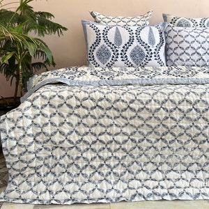K&ouml;nnte beinhalten: Eine wei&szlig;e und blaue Steppdecke mit geometrischem Muster. Die Steppdecke ist aus Baumwolle und f&uuml;hlt sich weich und bequem an.