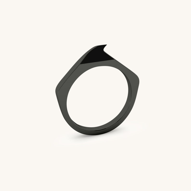 May include: A black ring with a sharp, angular design. The ring is made of a smooth, polished metal.