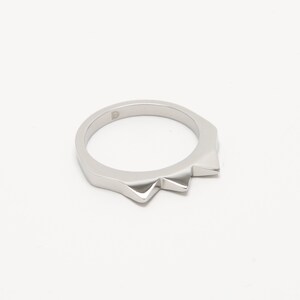K&ouml;nnte beinhalten: Ein silberner Ring mit einem spitzen, gezackten Randdesign.