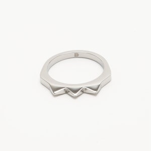 K&ouml;nnte beinhalten: Ein silberner Ring mit einem spitzen, gezackten Randdesign.