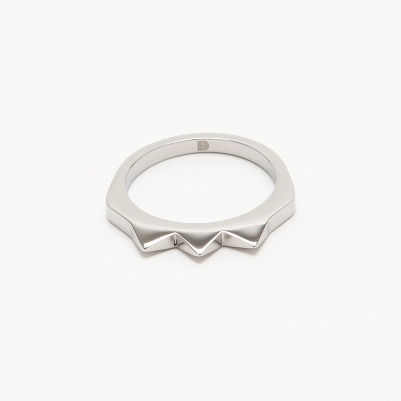 K&ouml;nnte beinhalten: Ein silberner Ring mit einem spitzen, gezackten Randdesign.