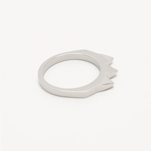K&ouml;nnte beinhalten: Ein silberner Ring mit einem spitzen, kronenartigen Design.