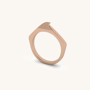 May include: A rose gold ring with a unique, angular design. The ring is made of a smooth metal and has a simple, modern style.